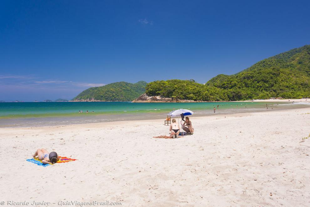 Imagem de duas amigas em baixo de guarda sol nas areias da Praia de Camburi.